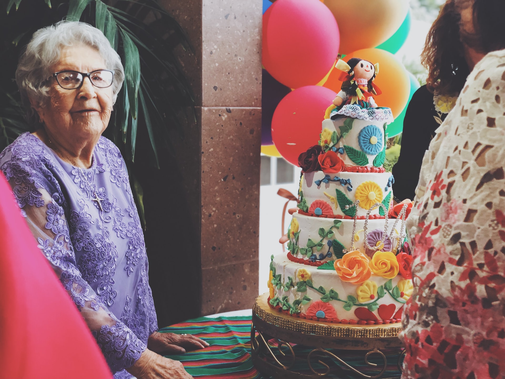 A woman wearing purple floral long-sleeved dress besides 4-layer cake photo